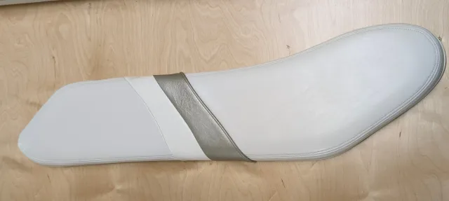 An old white bolster lying flat on the bench with a grey-gold strap across its middle.
