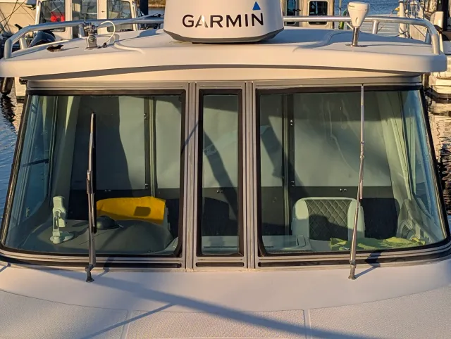 The boat's front windshield with the quilted helm seat visible inside and a radar dome above.