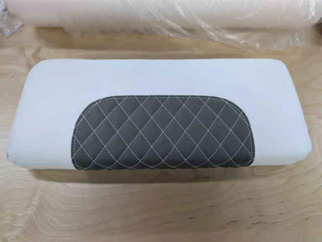 The top of a new white bolster with an oval charcoal diamond-quilted panel.
