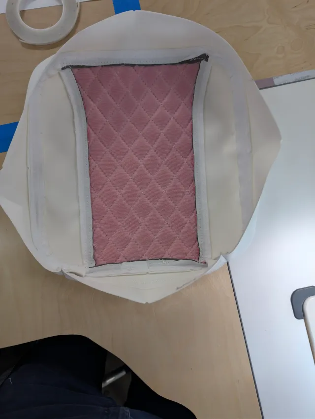 A cover turned inside out, showing pink quilted backing with white tape on the seams.