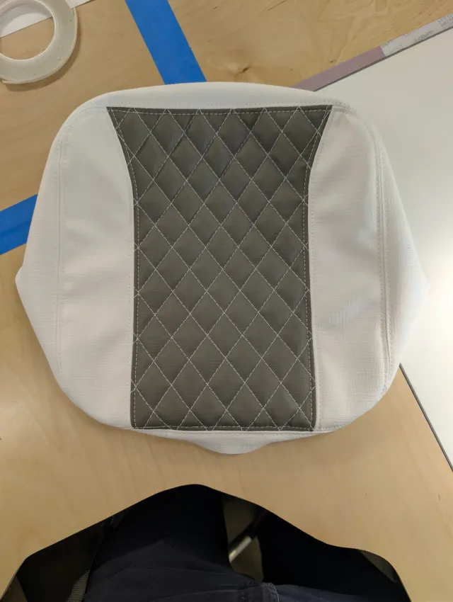 A finished cushion top cover, white sides with a charcoal diamond-quilted centre, on the bench.