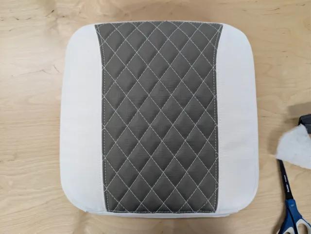 A new seat cushion with white sides and a charcoal diamond-quilted centre, on the bench.