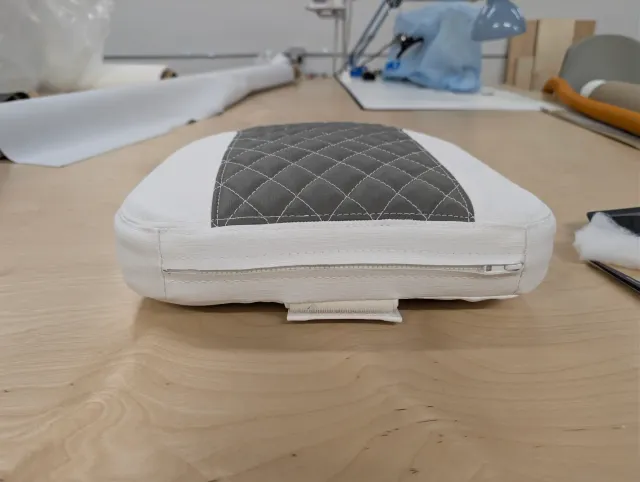 Front edge of a new seat cushion with a zipper in the boxing and a fabric tab beneath.