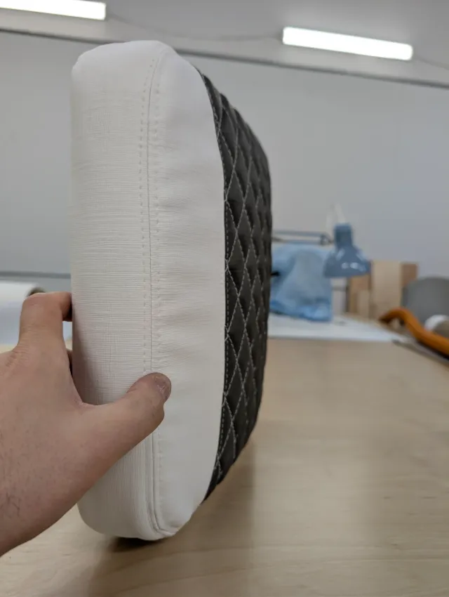 A new cushion held on edge, white boxing with a double-stitched seam beside the charcoal quilting.