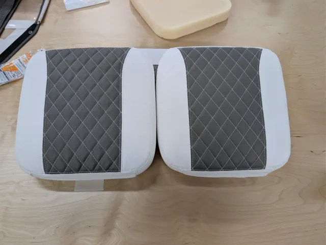 Two new seat cushions side by side, charcoal diamond-quilted centres on white, with a block of foam behind.