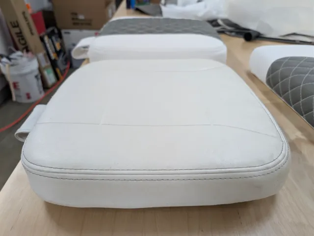 An old white seat cushion in front with new quilted cushions behind it.