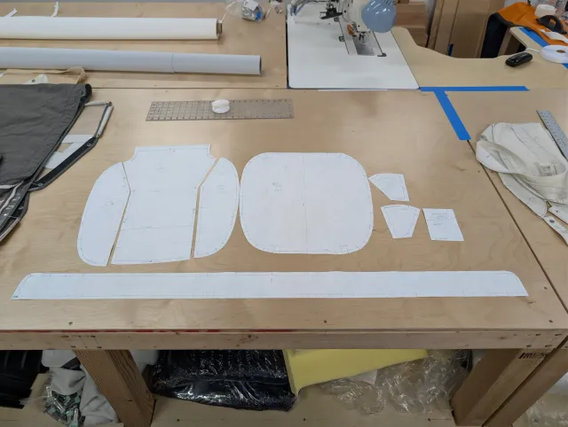 Paper patterns for a seat cushion laid out on the bench: top panels, a long boxing strip and small pieces.