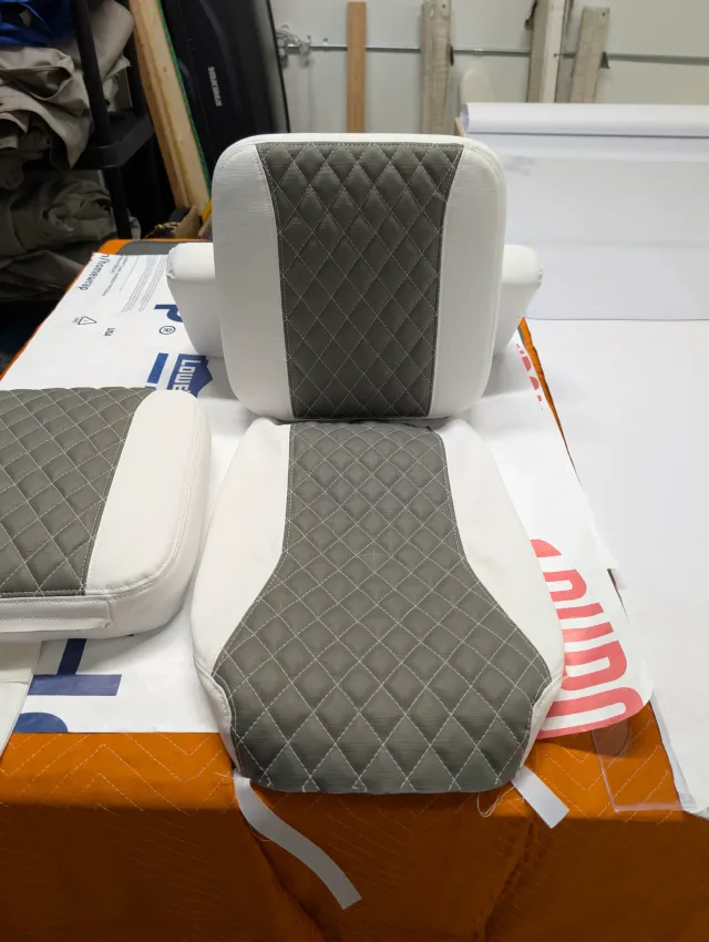 A new seat bottom and back cushion stacked on the bench, white with charcoal quilted centres, another cushion at left.