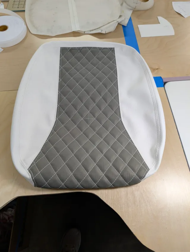 A new seat bottom with white sides and a charcoal quilted centre that widens at the front.
