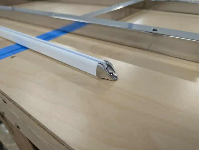 Close-up of a white track with a polished stainless end cap, the stainless frame behind it.