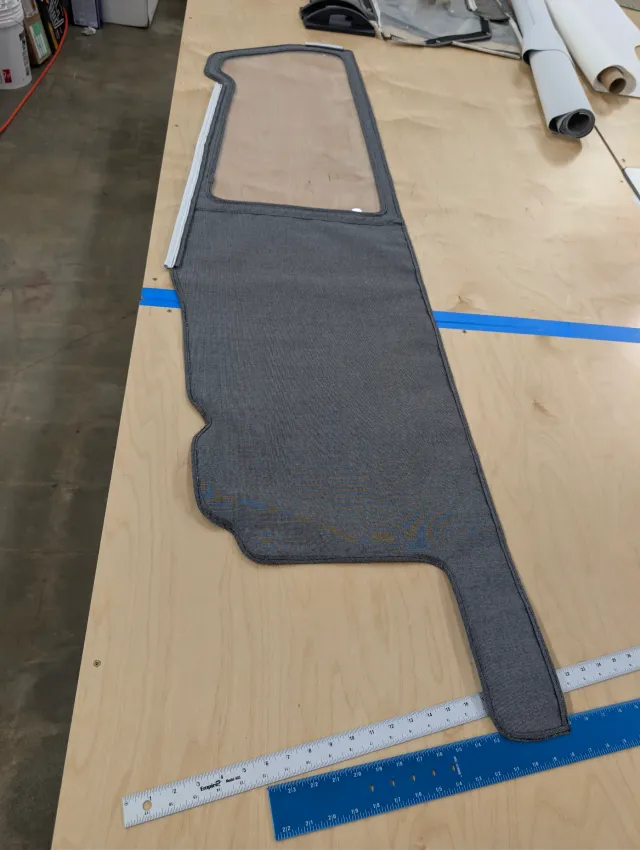 A long charcoal curtain section with a clear window at the top and white track along one edge, rulers beside it.