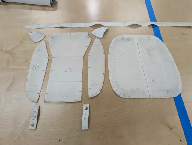 Pieces of an old cushion cover laid flat on the bench, marked with part names and port and starboard.