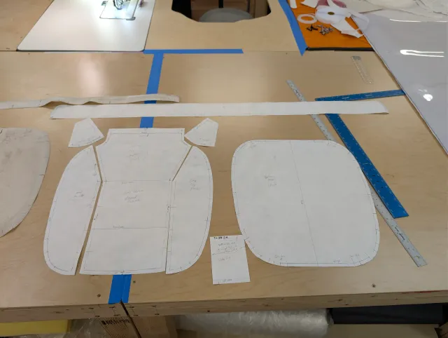 Paper patterns laid beside the old cover's pieces on the bench, with rulers and a long strip above.