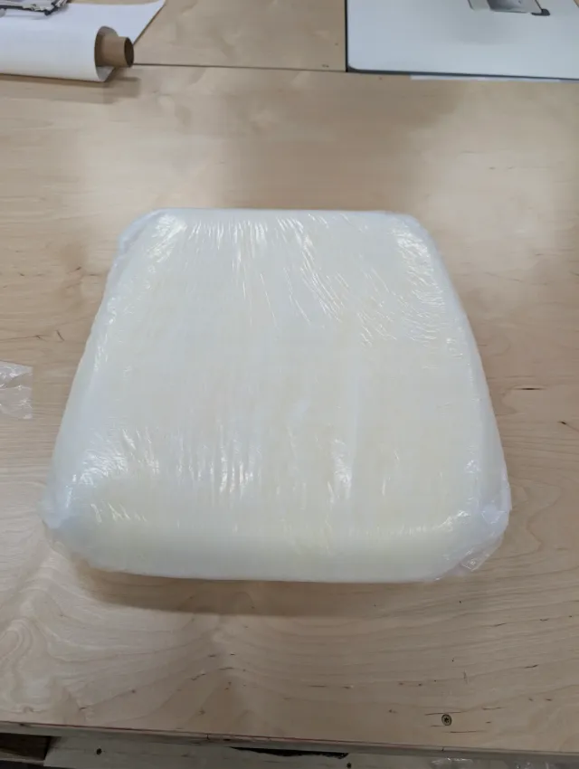 A foam cushion insert fully wrapped in white batting and clear film.