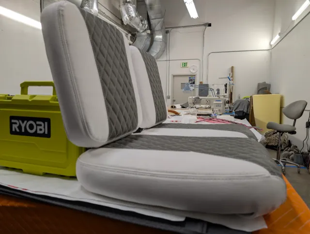 Low side view of a new seat back and seat bottom, the workshop behind.