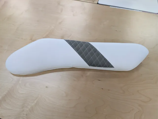 A finished curved bolster, white with a diagonal charcoal quilted panel.