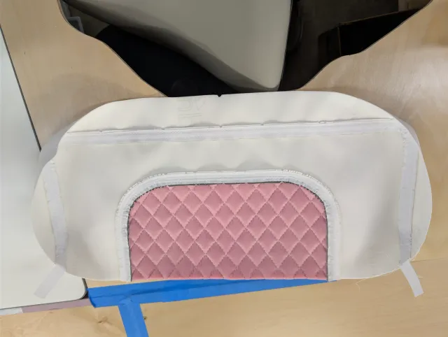 A bolster cover inside out with an oval pink quilted panel and taped seams.