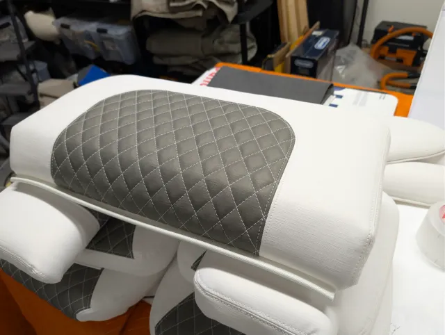 A bolster with an oval charcoal quilted top resting on other new cushions.
