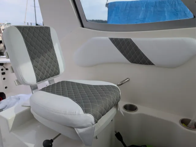 The helm seat and a wall bolster installed on the boat, white with charcoal diamond quilting.