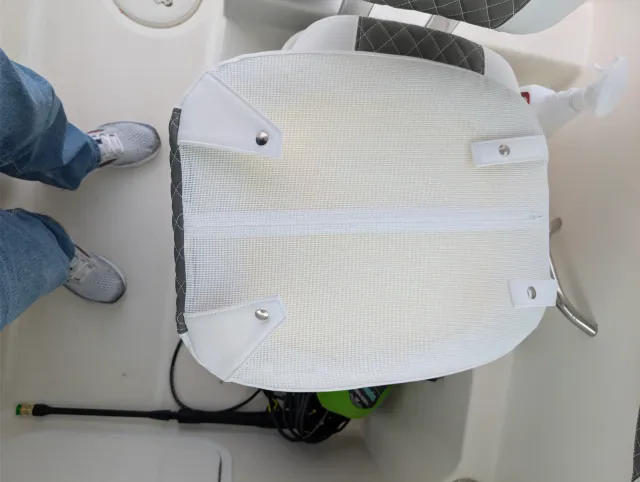 The mesh back of a cushion lying in the cockpit with its snaps fastened to the tabs.