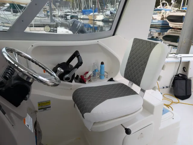 The helm seat installed in the cockpit beside the steering wheel, marina behind.