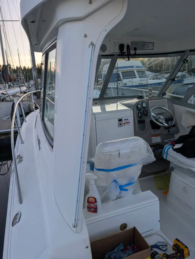 White track running down the side post of the cabin top, seats wrapped in plastic below, marina beyond.
