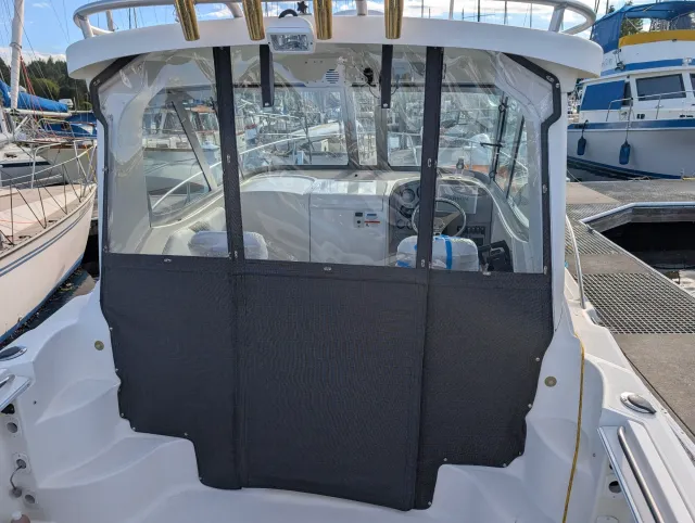 The new aft enclosure on the boat, charcoal lower panels and clear windows, with vertical straps between the sections.