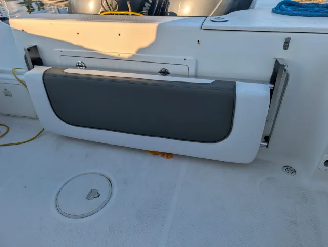 The aft fold-up seat stowed upright against the transom, its charcoal panel facing out.