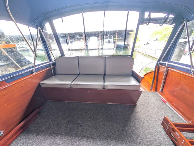 The flybridge aft settee with its old grey vinyl cushions in place, the marina beyond the windows.