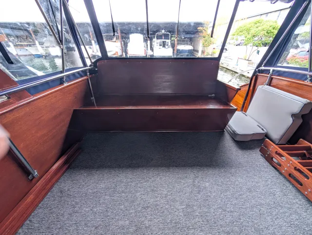 The varnished flybridge settee with its cushions removed, grey carpet on the floor.