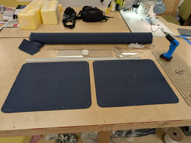 Two navy Sunbrella panels cut for cushion tops on the loft bench, foam blocks behind them.