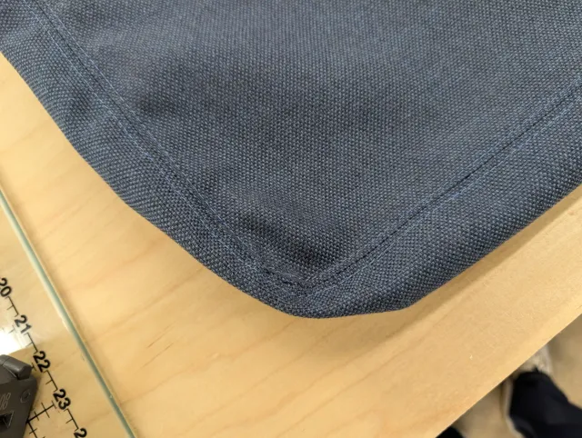 The corner of a finished navy cushion cover, French seams meeting at a square corner.