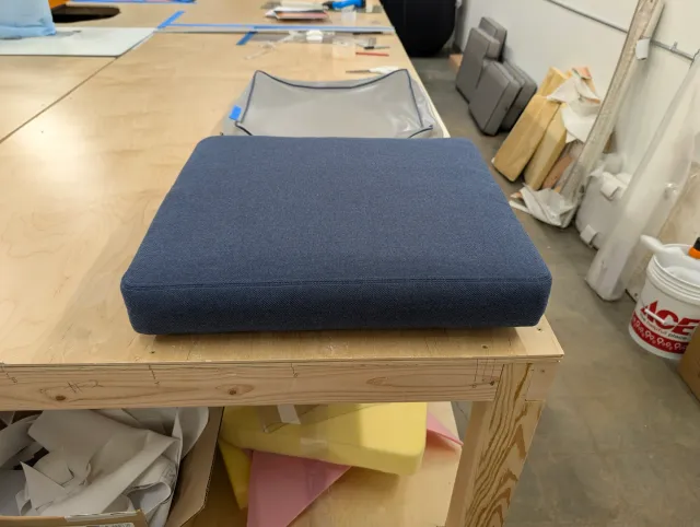 A finished seat cushion on the loft bench, square and crowned.