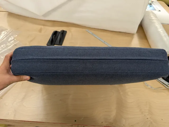 A finished back cushion held edge-on, the zipper running along its back boxing.