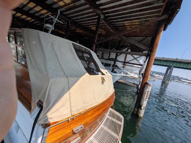 The varnished wood motor cruiser in its boathouse with the aft deck cover in place.