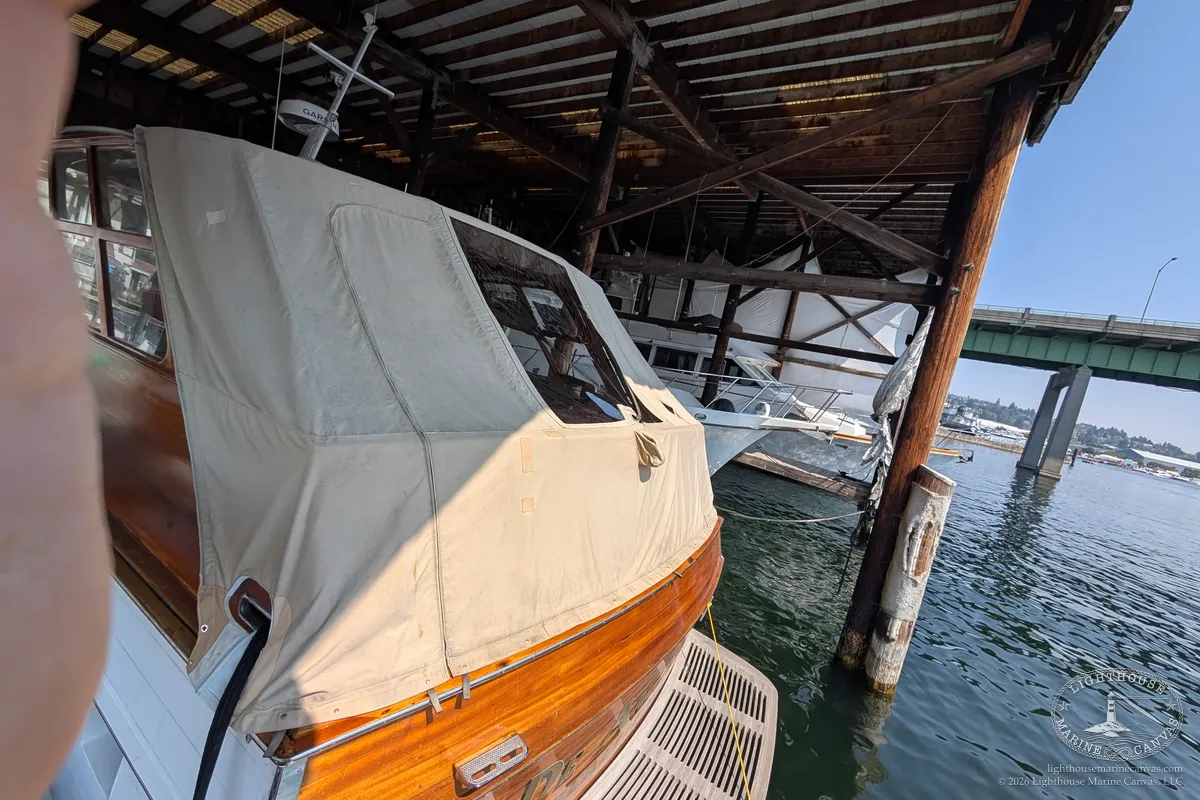 The varnished wood motor cruiser in its boathouse with the aft deck cover in place.
