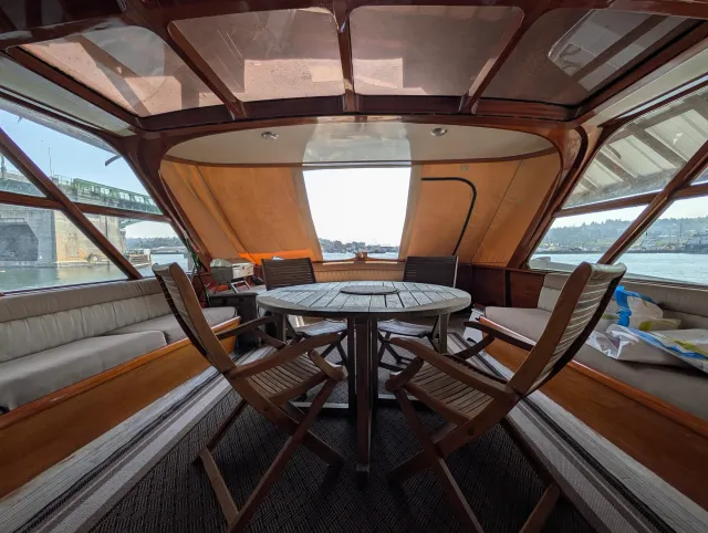 The aft deck under the cover, a teak table and chairs, light coming through the new window.