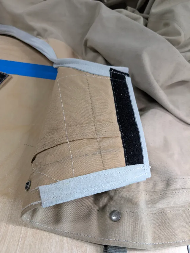 A corner of the cover with bound edges, a hook-and-loop strip and snaps.