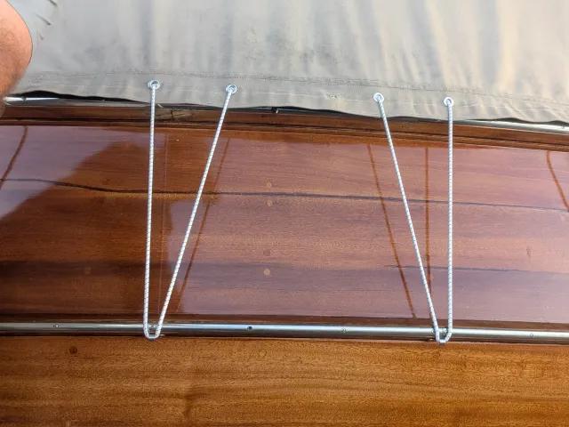 Shock cord loops from the cover's lower edge to the stainless rail on the varnished transom.