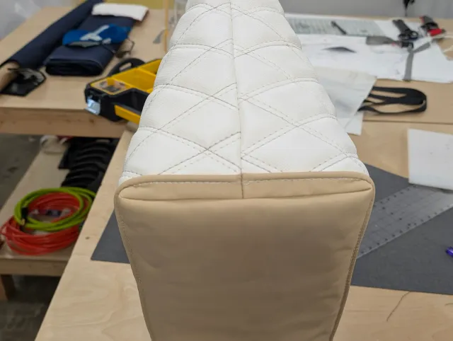 The narrow end of the tote, white diamond quilting above a tan panel with a centre seam.