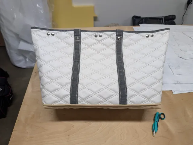 The other side of the quilted tote with two grey straps and silver rivet heads in pairs near the top edge.