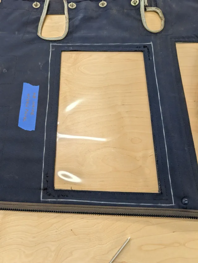 A navy enclosure panel lays flat on the workbench, its old window edge outlined in chalk.